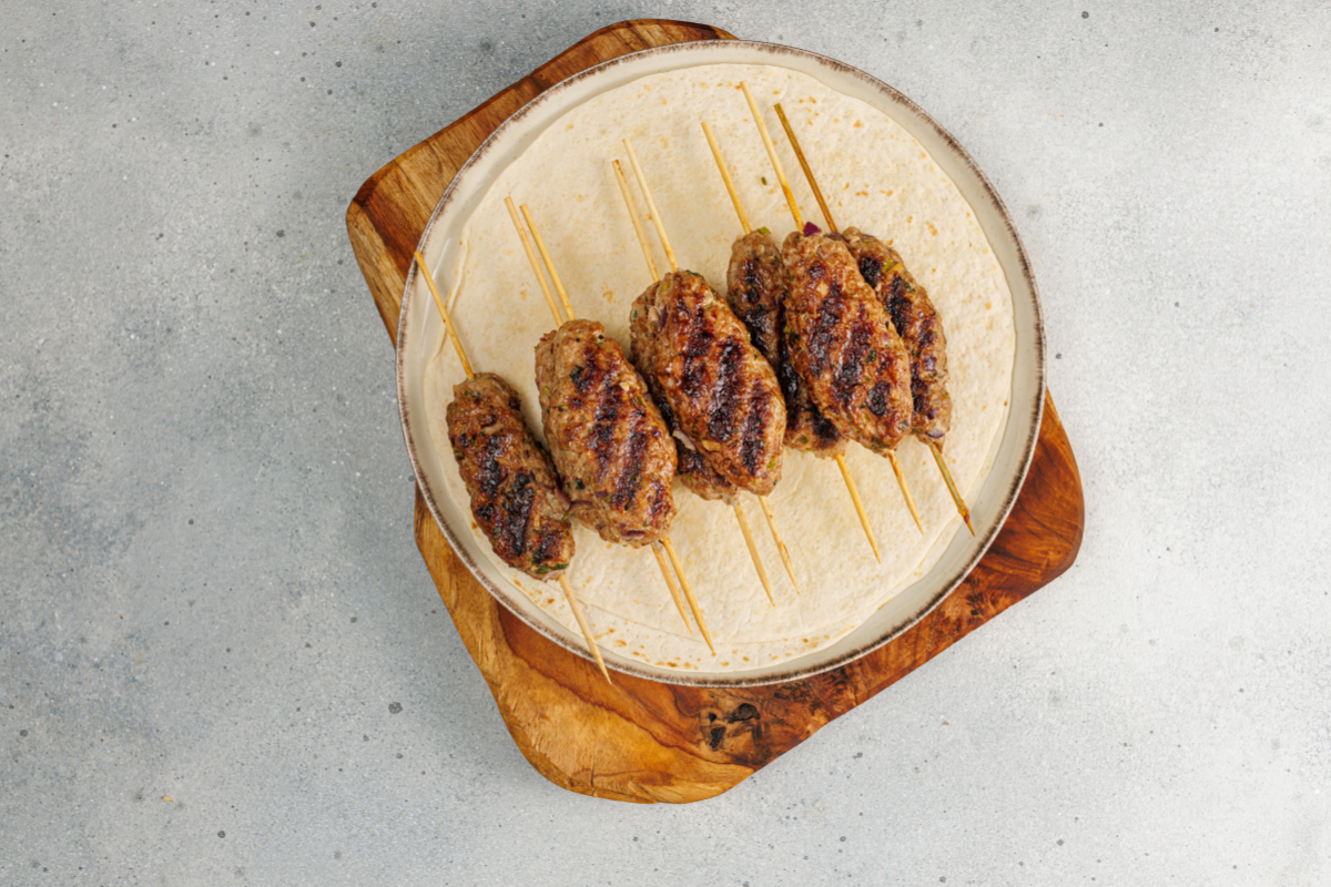 Grilled homemade kofte kebabs served on a wooden board after cooking until beautifully browned.