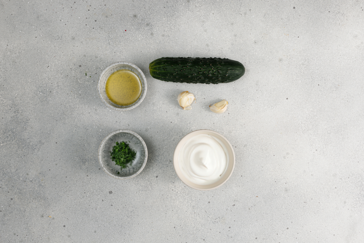 Greek yogurt, cucumber, garlic, lemon, dill, and olive oil prepared for homemade tzatziki.