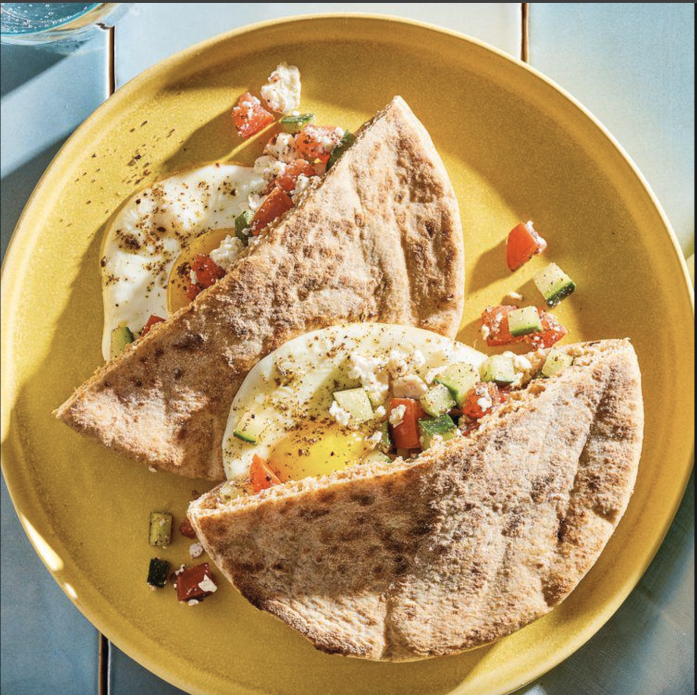 Egg, Tomato and Feta Breakfast Pita served with sunny-side-up eggs, fresh cucumber, juicy tomatoes, crumbled feta, and za'atar in warm whole-wheat pita bread.
