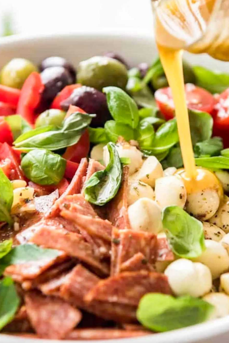 Fresh Spaghetti Salad topped with cherry tomatoes, cucumbers, bell peppers, black olives, and grated Parmesan.