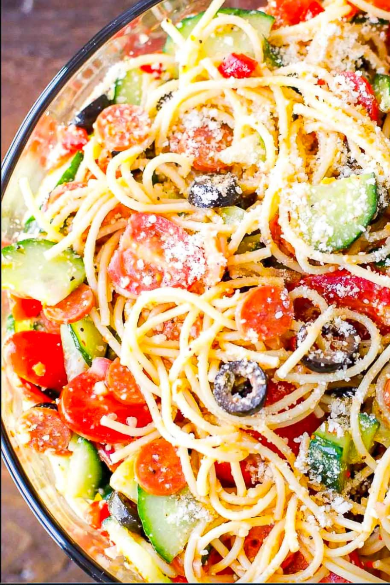 Cooked spaghetti and fresh vegetables combined in a large bowl before adding Italian dressing.