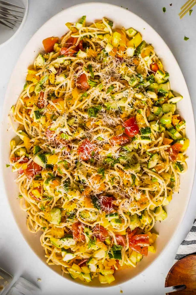Easy Spaghetti Salad with fresh vegetables, black olives, Parmesan cheese, and Italian dressing served in a large white bowl.