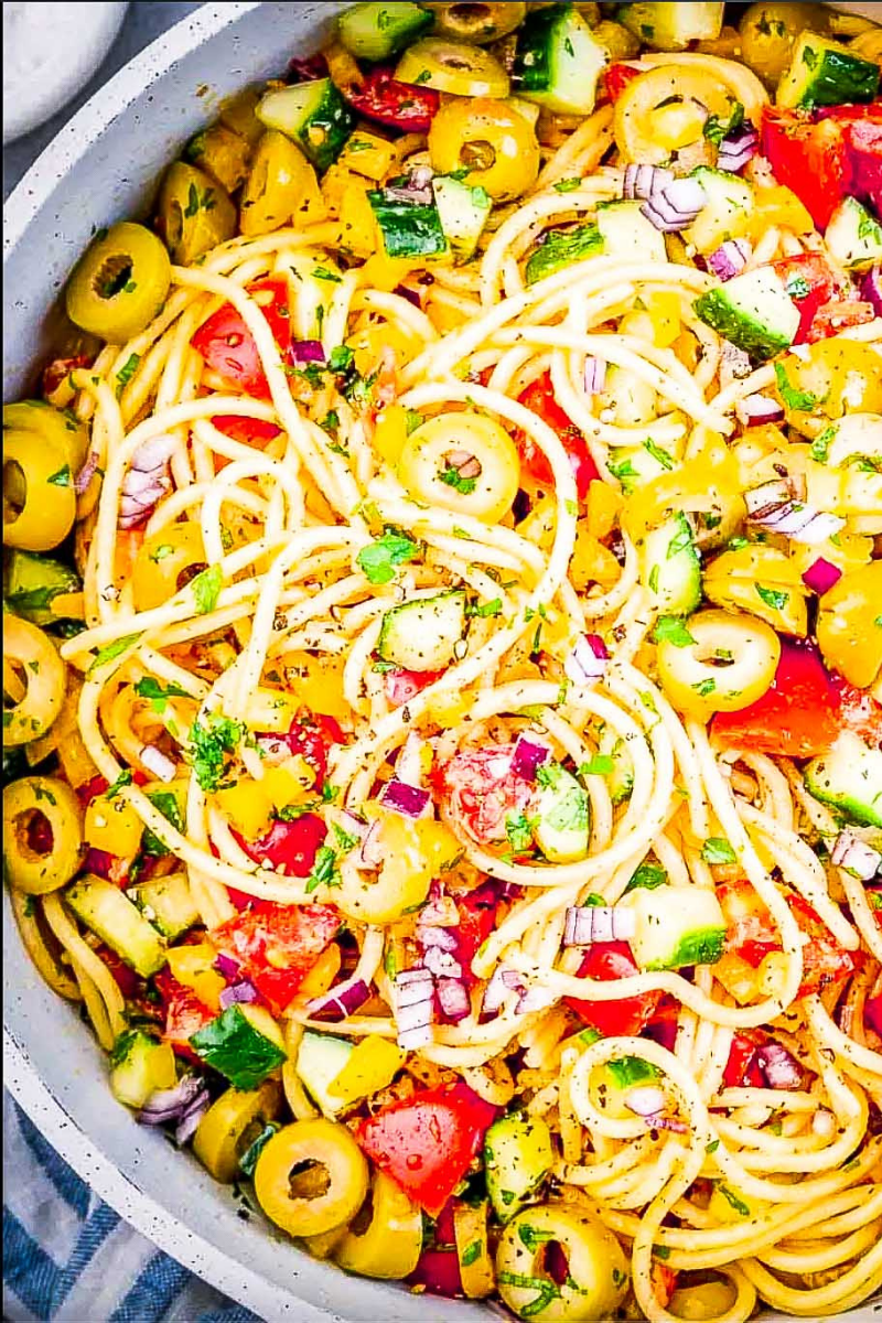 Homemade Spaghetti Salad tossed with colorful vegetables and Italian dressing, ready to chill before serving.