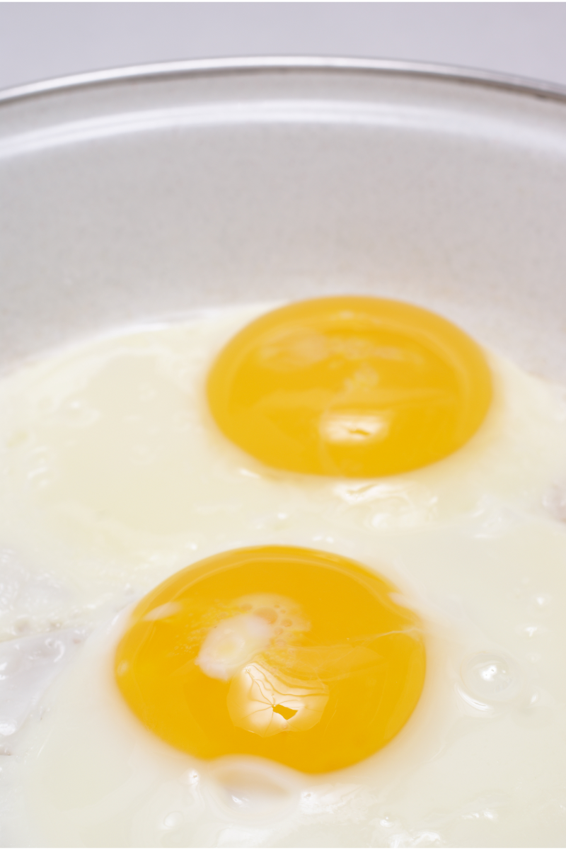 Eggs cooking in a nonstick skillet while whole-wheat pita warms nearby.