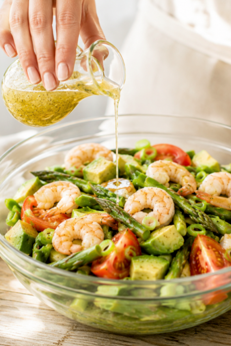 poring the Dijon dressing over the asparagus and shrimp salad