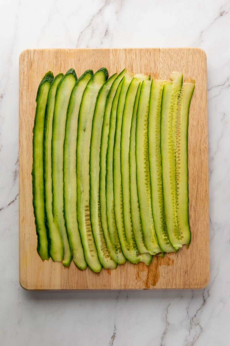Overlapping cucumber ribbons to create the base for Everything Bagel Cucumber Rolls before adding the filling.