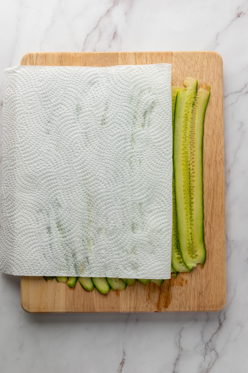 Layering smoked salmon over cream cheese and sprinkling everything bagel seasoning on cucumber ribbons.