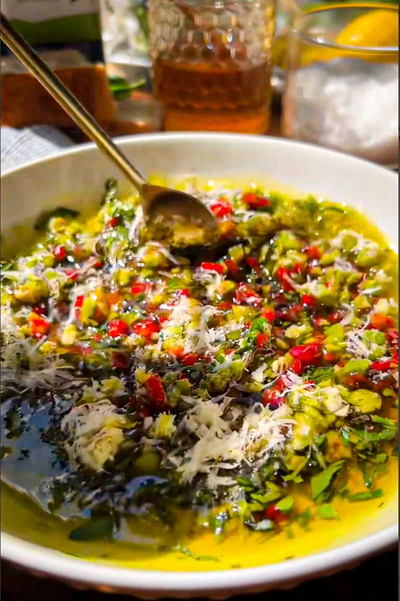 Smoky Mediterranean bread dip with olive oil, chopped vegetables, olives, and fresh herbs.