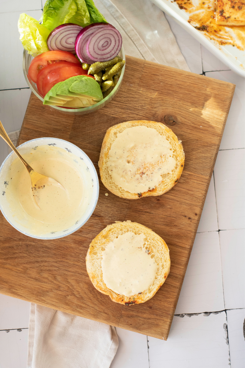 Toasted burger buns spread with creamy garlic lemon sauce before assembling halloumi burgers.