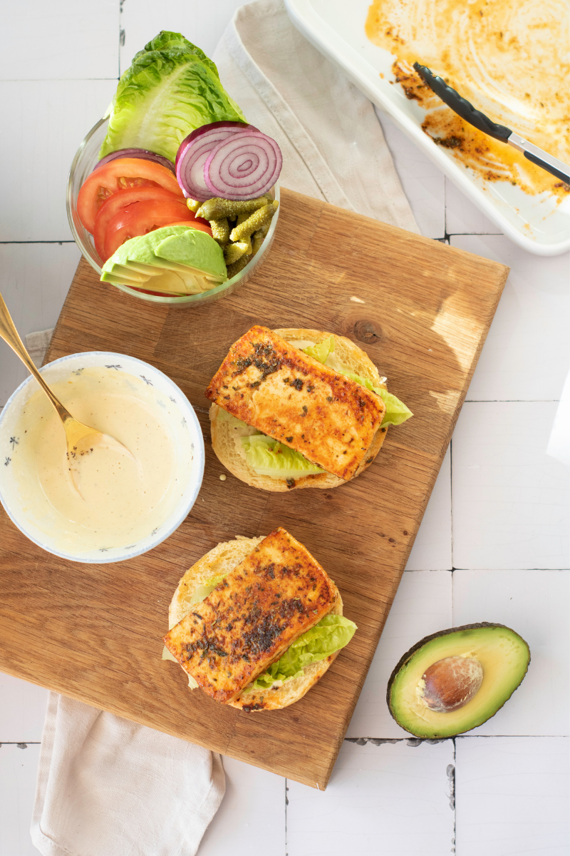 Golden halloumi cheese placed over lettuce on toasted buns while assembling halloumi burgers.