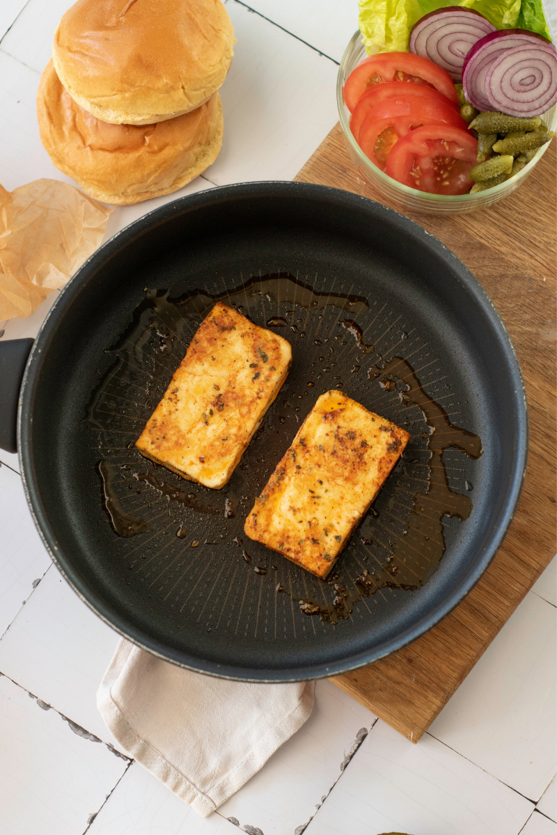 Halloumi cheese slices frying in a skillet until golden brown for homemade halloumi burgers.