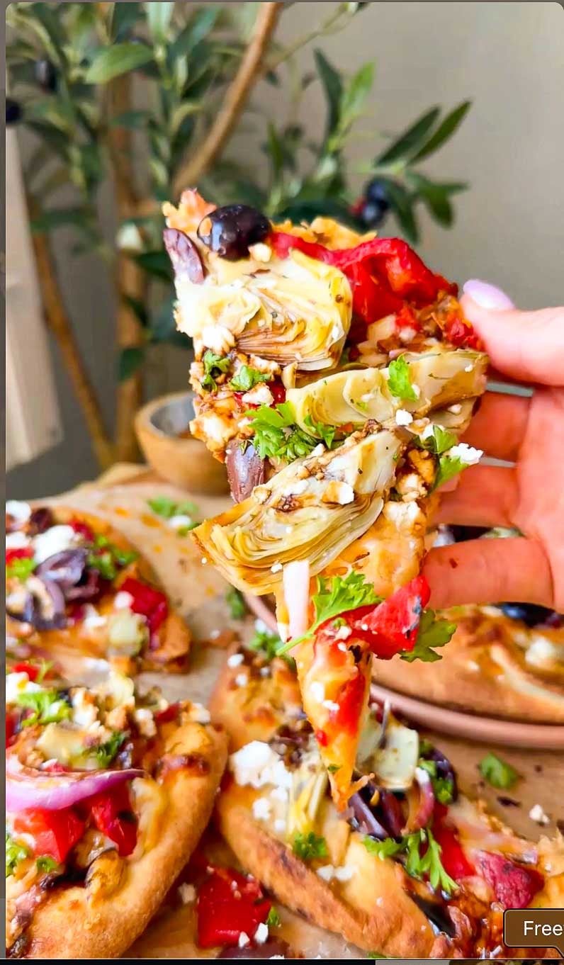 Sliced Mediterranean flatbread topped with hummus, vegetables, mozzarella and feta