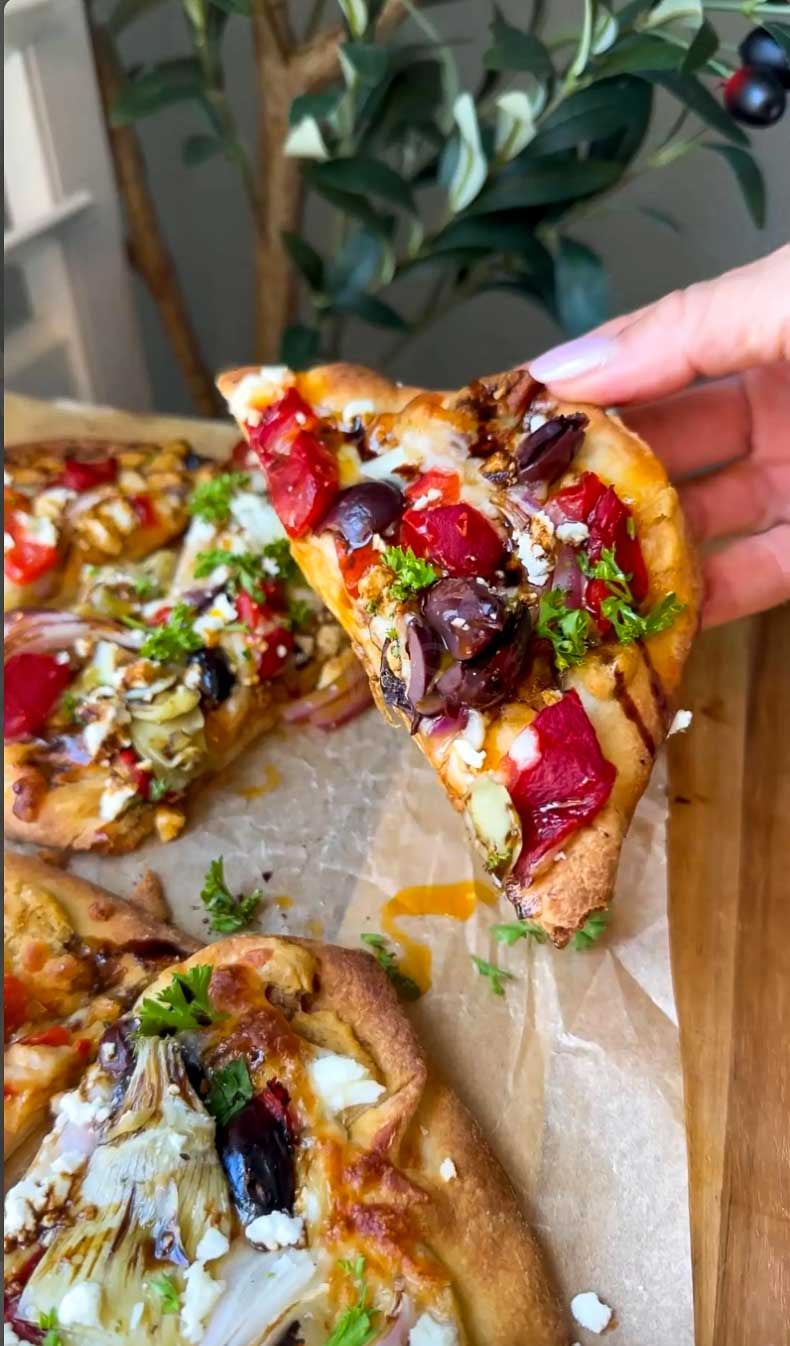 Mediterranean hummus flatbread with colorful vegetables and melted cheese