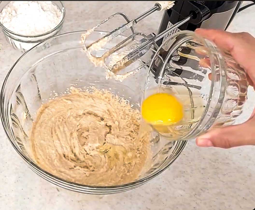 Egg being mixed into creamed butter and brown sugar for baklava cookies.