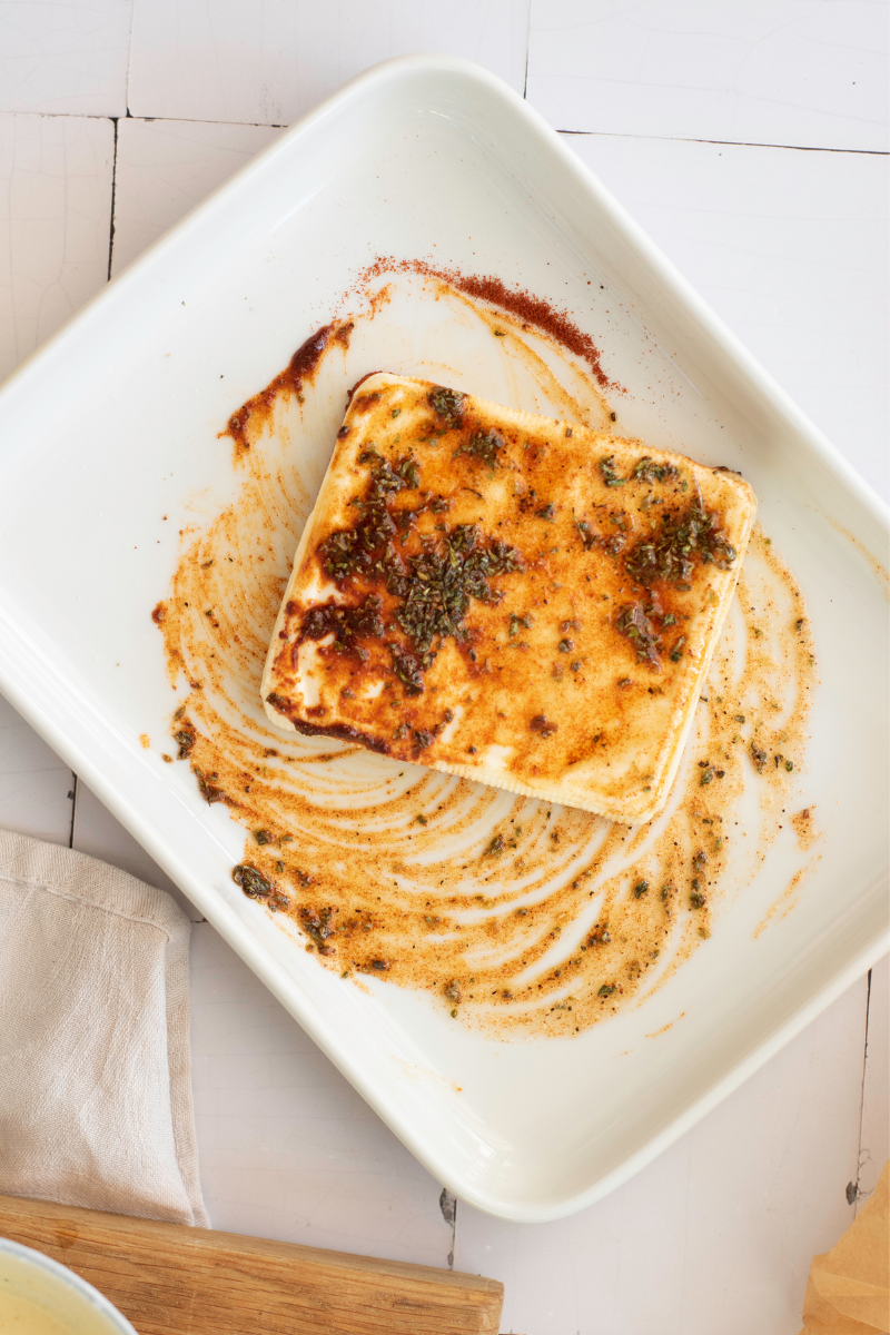 Halloumi slices coated with olive oil, oregano, paprika, salt, and black pepper before cooking.