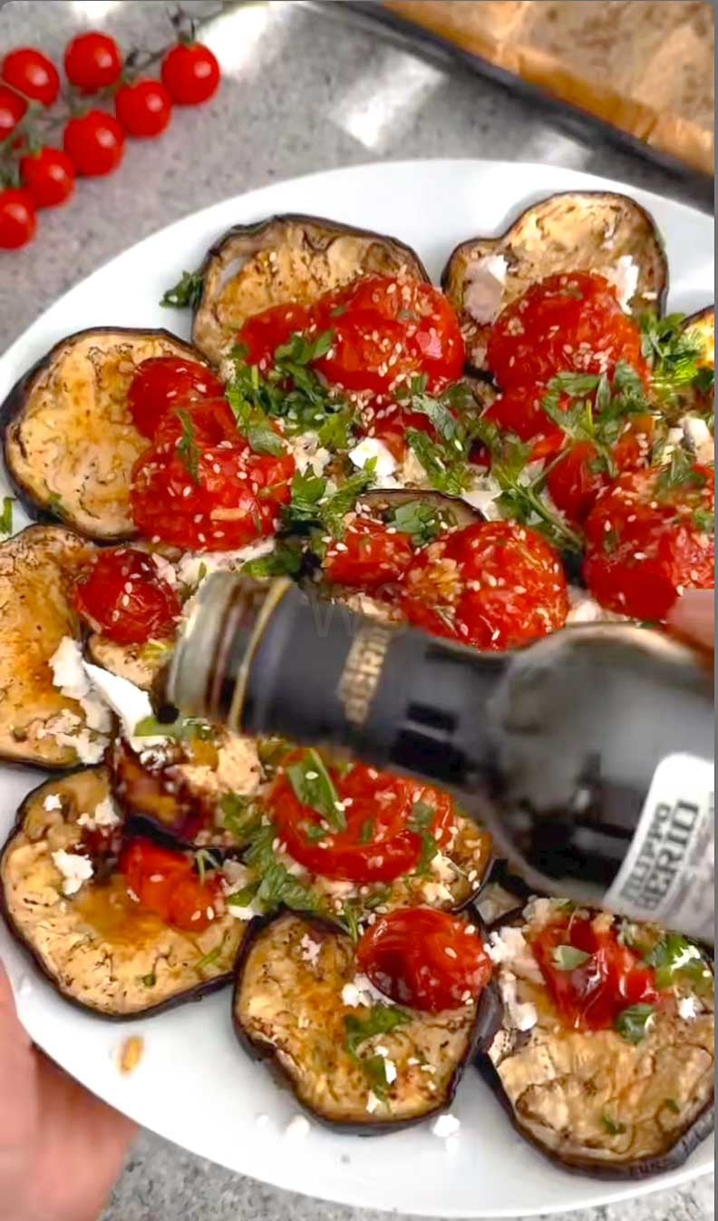 Roasted eggplant rounds topped with tomatoes, crumbled feta, fresh parsley, and balsamic glaze