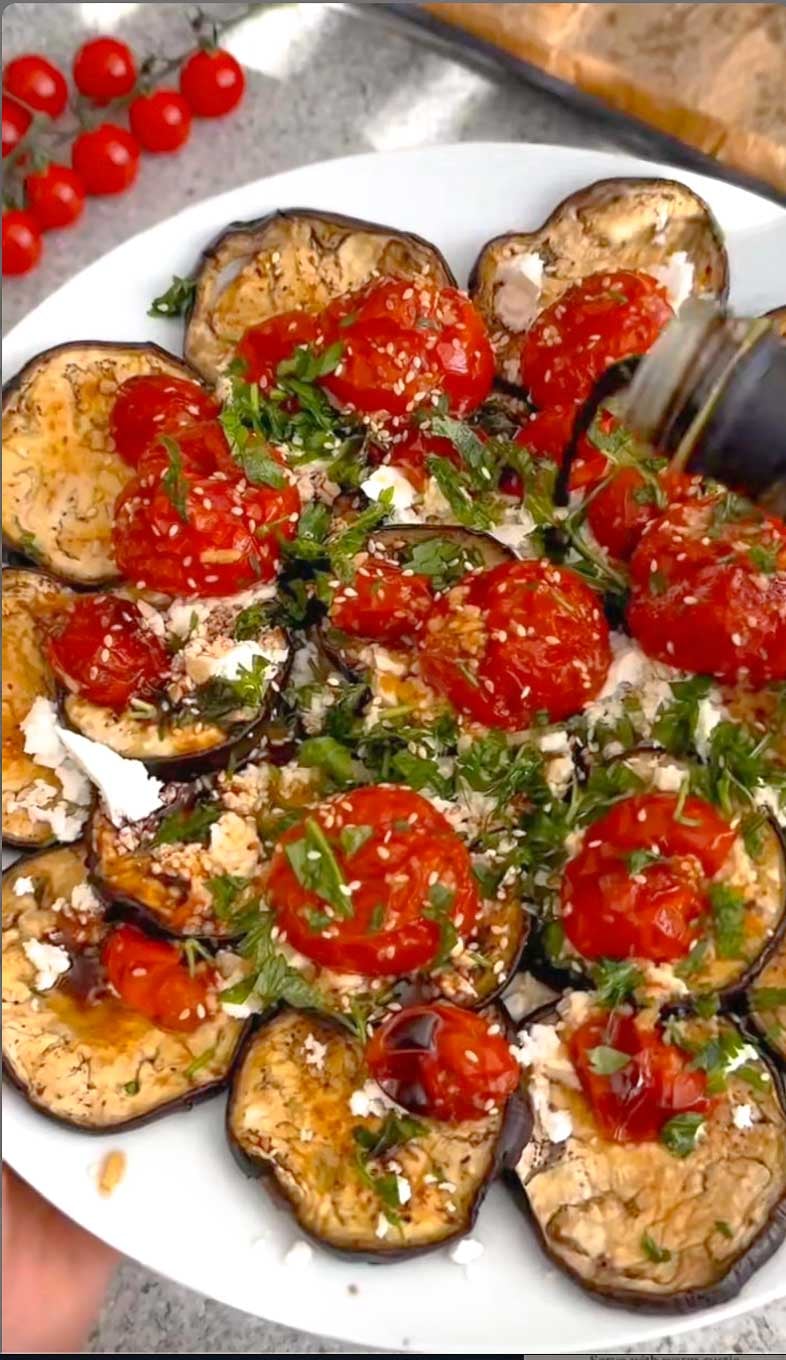 Mediterranean roasted eggplant platter with cherry tomatoes, feta, parsley, sesame seeds, and balsamic glaze