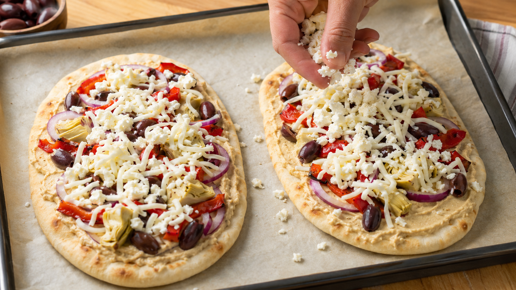 Mediterranean flatbreads topped with shredded mozzarella and crumbled feta before baking
