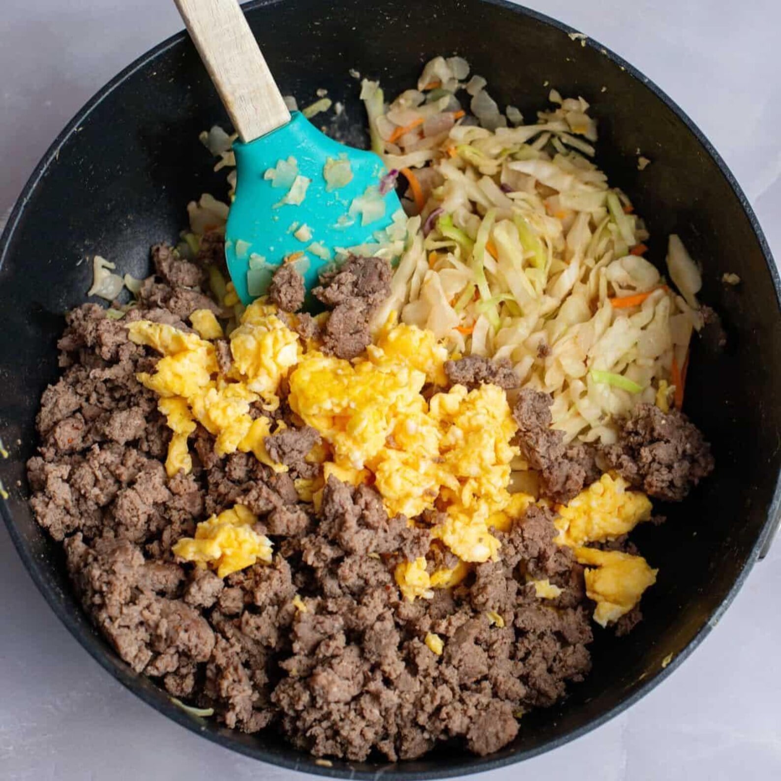 Cooked turkey sausage, scrambled eggs and cabbage combined in a skillet for Egg Roll in a Bowl.