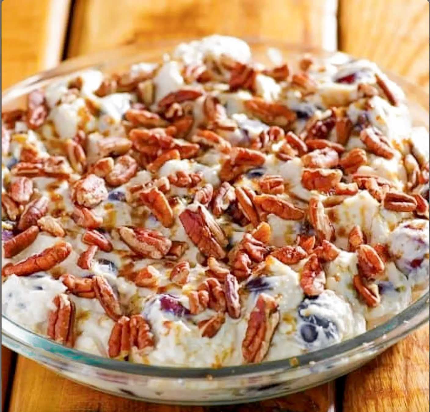 Finished Southern grape salad with fresh seedless grapes in creamy dressing topped with chopped pecans.