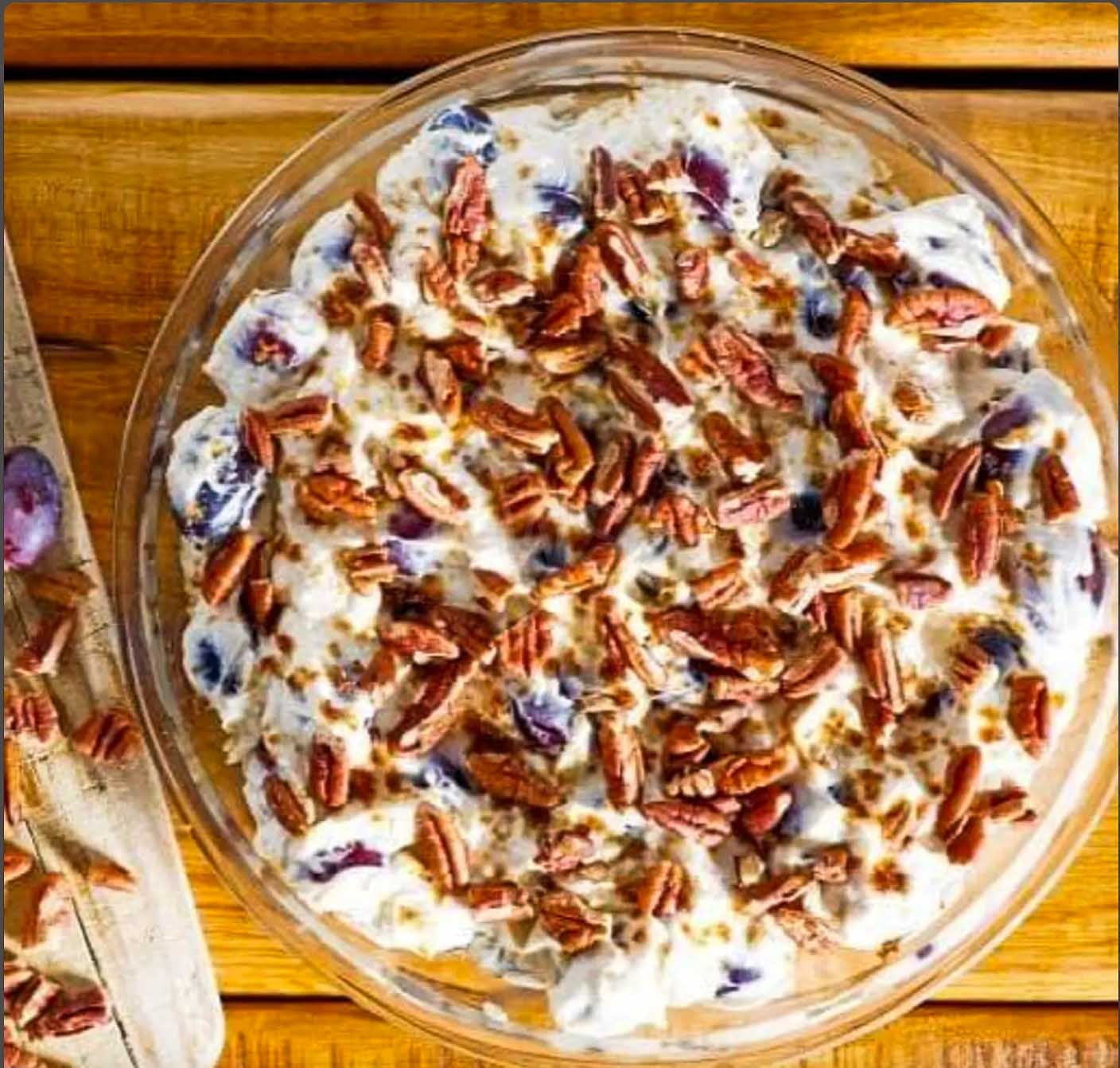 Finished Southern grape salad with fresh seedless grapes in creamy dressing topped with chopped pecans.