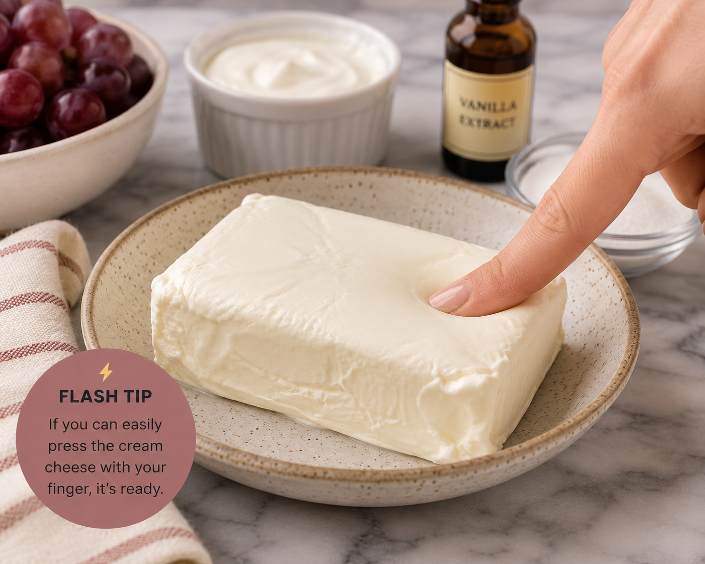 Softened cream cheese being gently pressed to check that it is ready for Southern grape salad.