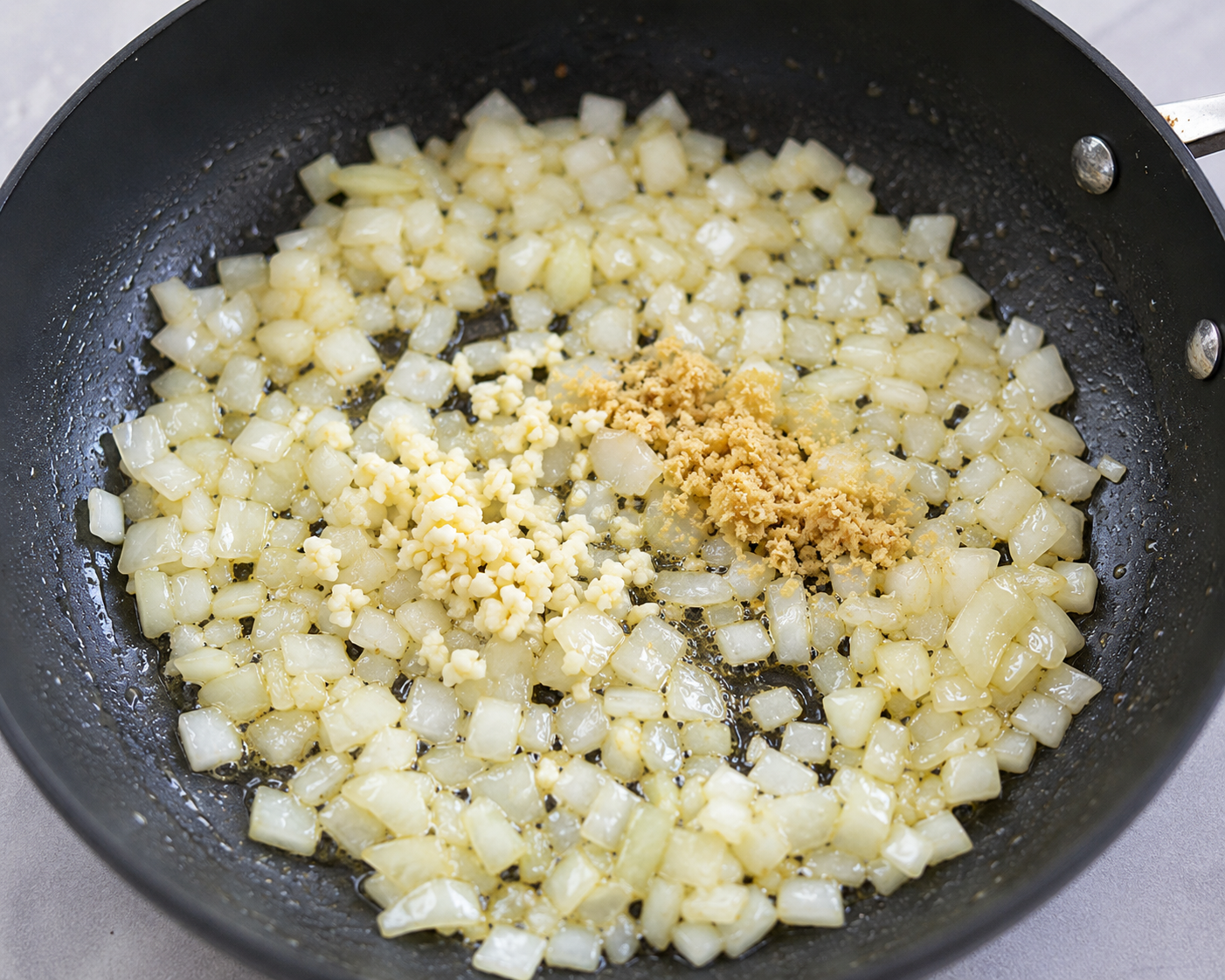 Diced onion, garlic and ground ginger sautéing in a skillet for Egg Roll in a Bowl.