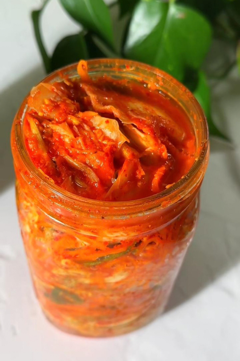Homemade Western-style kimchi with spicy fermented Napa cabbage packed in a glass jar.