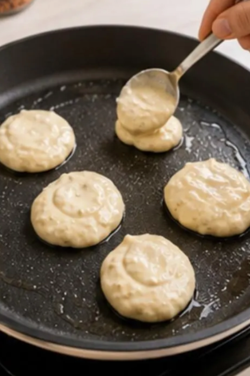 Small pancake bites with fresh blueberries cooking in a skillet over medium-low heat