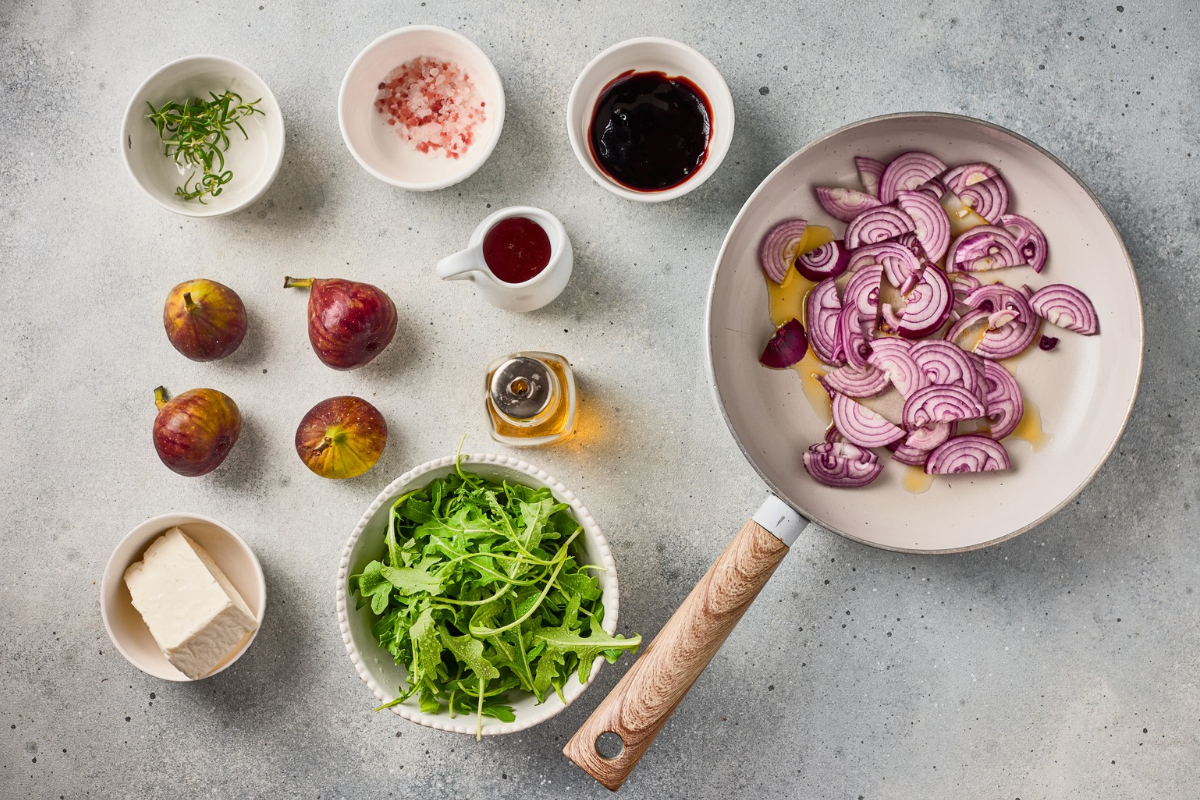 Thinly sliced red onions beginning to cook in olive oil in a skillet for fig flatbread.