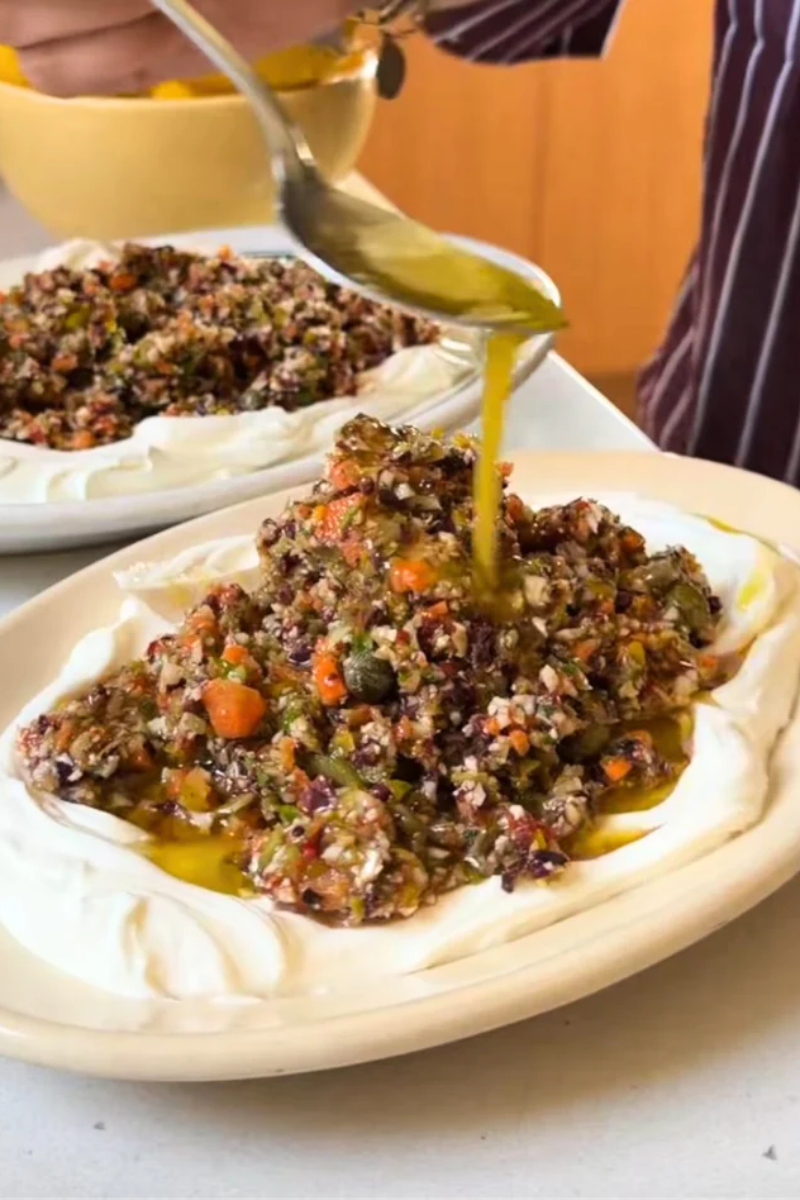 Mediterranean olive salad with chopped Kalamata and Castelvetrano olives, colorful vegetables, fresh herbs, and creamy labneh.