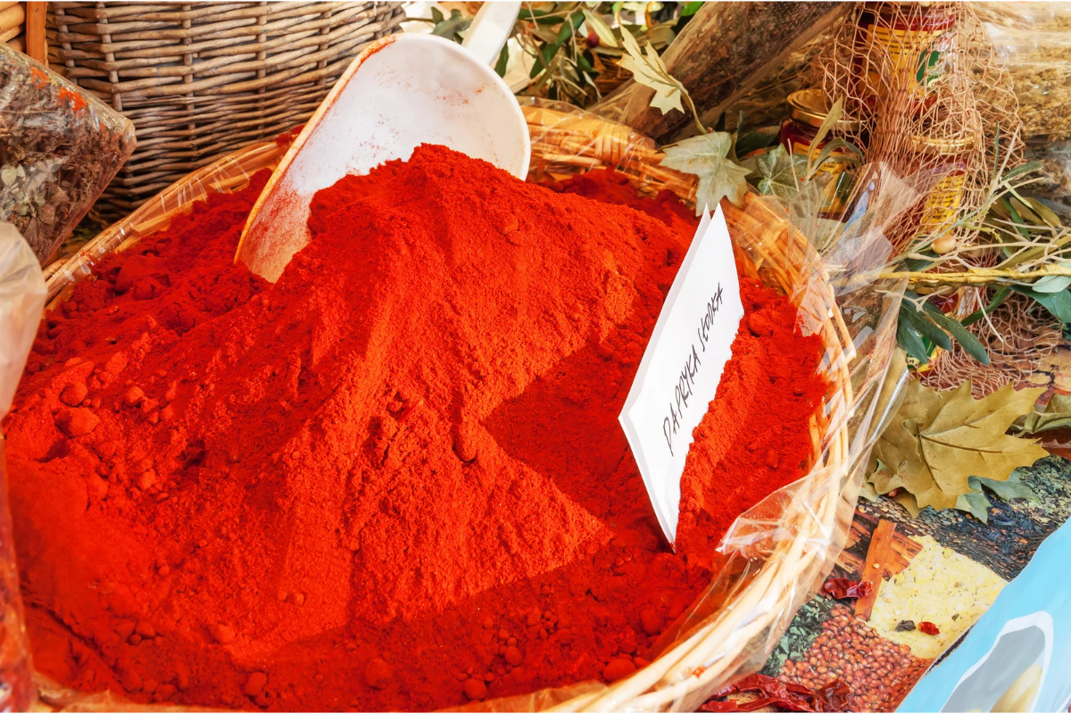 Mini pumpkin cheese ball being rolled in red paprika coating for a festive Fall, Autumn, and Thanksgiving appetizer.